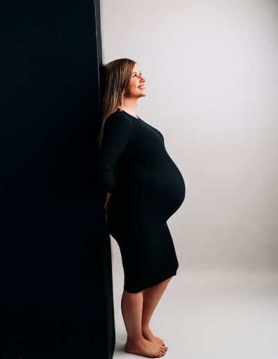 Sesión de fotos de embarazo en estudio en Jerez con fondo blanco y pared negra, futura mamá en perfil