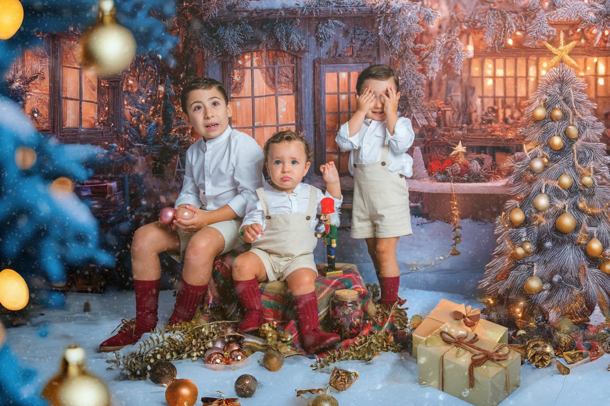 Dos hermanos sonríen junto al árbol Niño disfrutando del escenario navideño 2025 en Jerez en Estudio José Cáceres Fotografía.