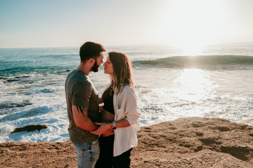 Pareja esperando un bebé paseando por la orilla de la playa de Barbate en invierno.