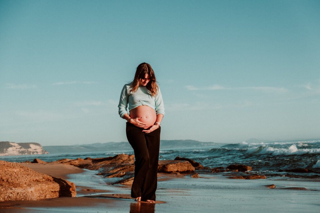 Pareja esperando un bebé paseando por la orilla de la playa de Barbate en invierno.