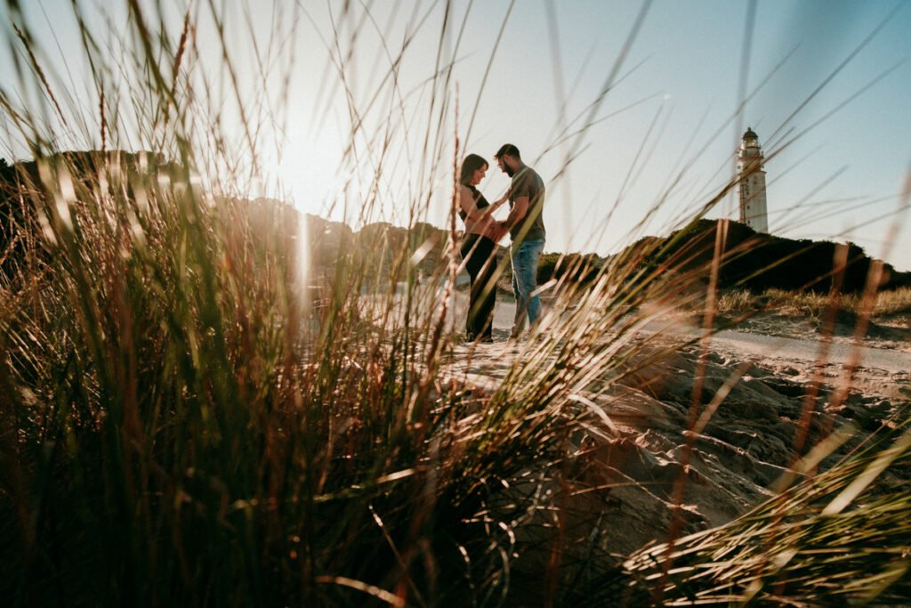 Pareja esperando un bebé paseando por la orilla de la playa de Barbate en invierno.