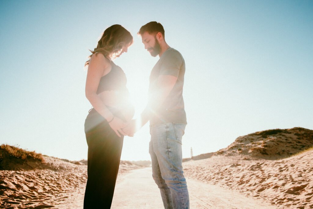 Primer plano de barriga de embarazada en entorno natural de dunas en Cádiz.